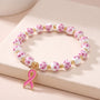 Close-up pink ribbon beaded bracelet with white and pink floral beads and gold beads