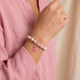 Pink ribbon charm bracelet with white and pink floral beads and gold accents