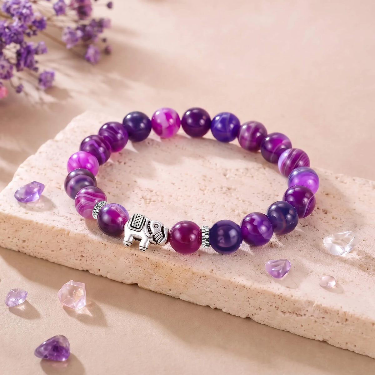 Amethyst bead bracelet with elephant charm, purple and pink beads on stone slab
