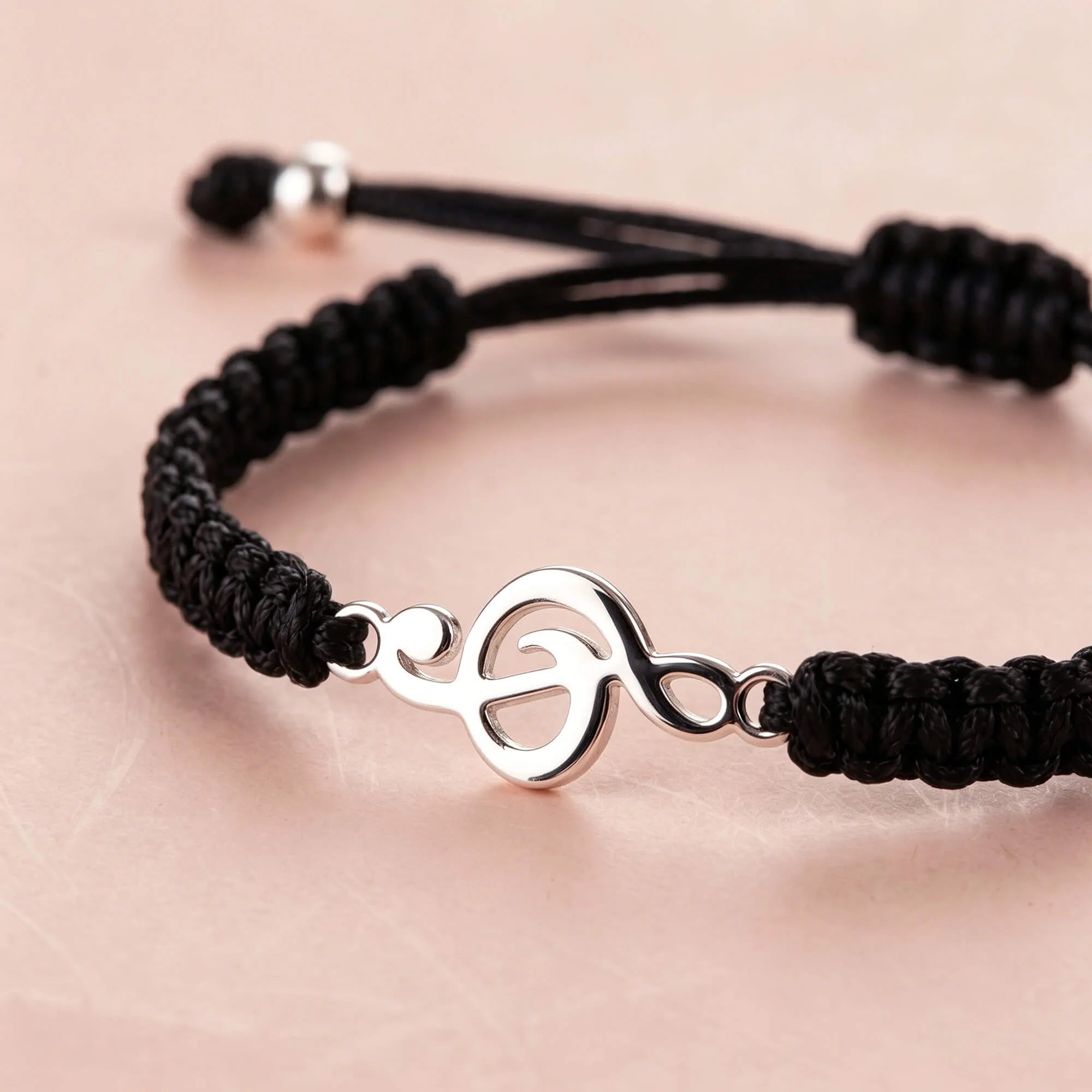 Close-up of black bracelet with treble clef charm