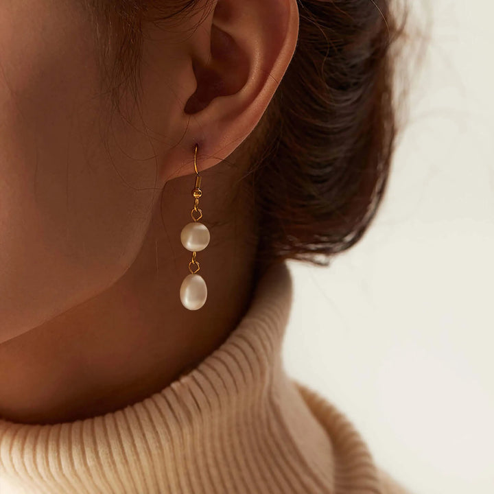 Gold-tone double freshwater pearl drop earrings worn by a model