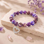 Purple beaded bracelet on light stone with silver heart charm