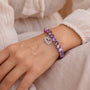 Purple bead bracelet with silver heart charm on wrist