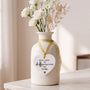 Ceramic heart keepsake with gold ribbon hanging from a vase