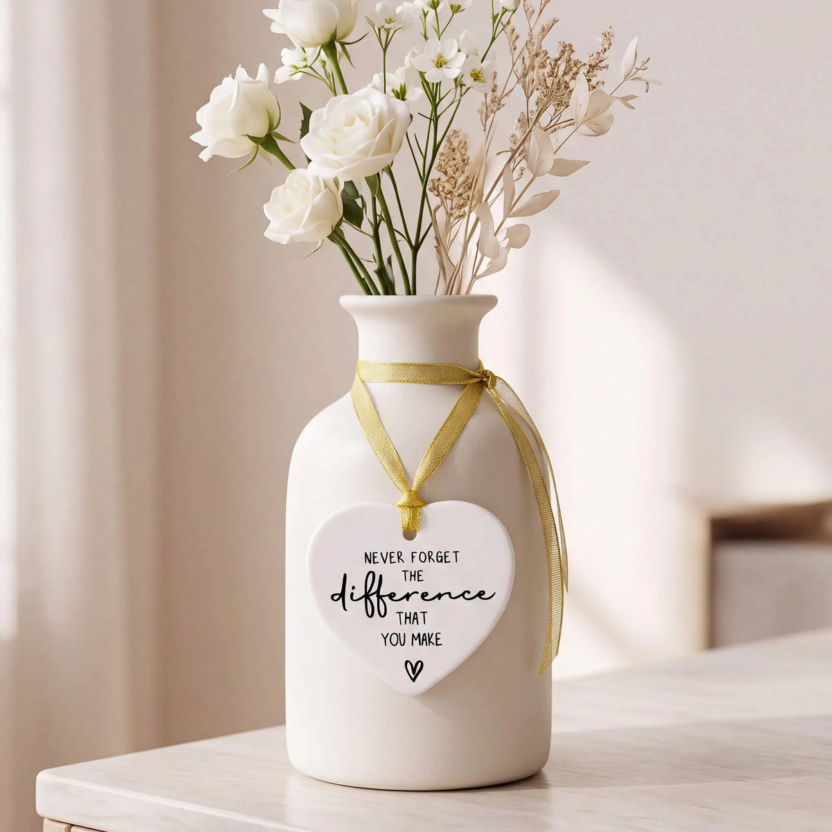 Ceramic heart keepsake with gold ribbon hanging from a vase