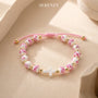 Bracelet with pink floral beads and a white cross on the table