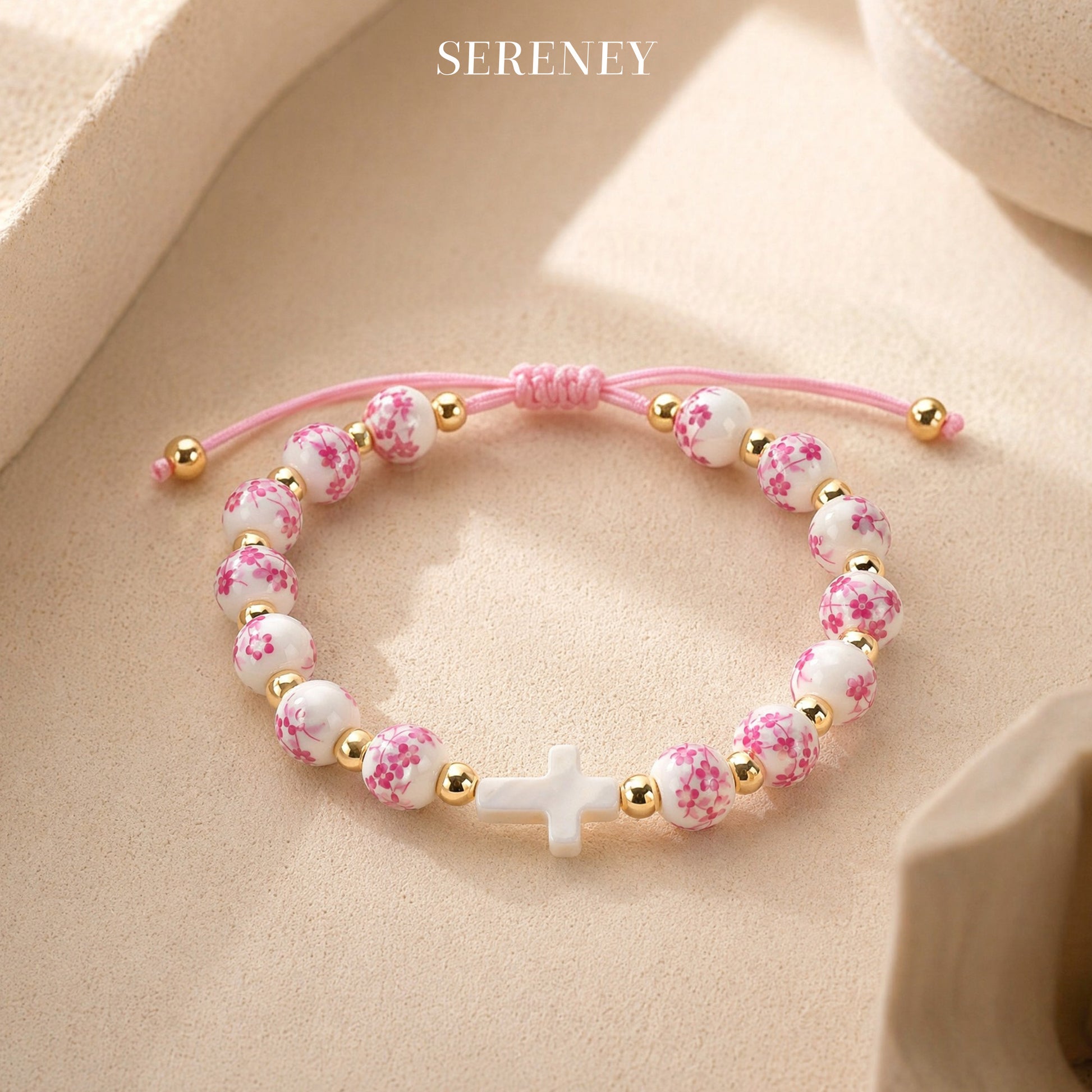 Bracelet with pink floral beads and a white cross on the table