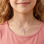 Girl wearing silver cross necklace with butterfly charm