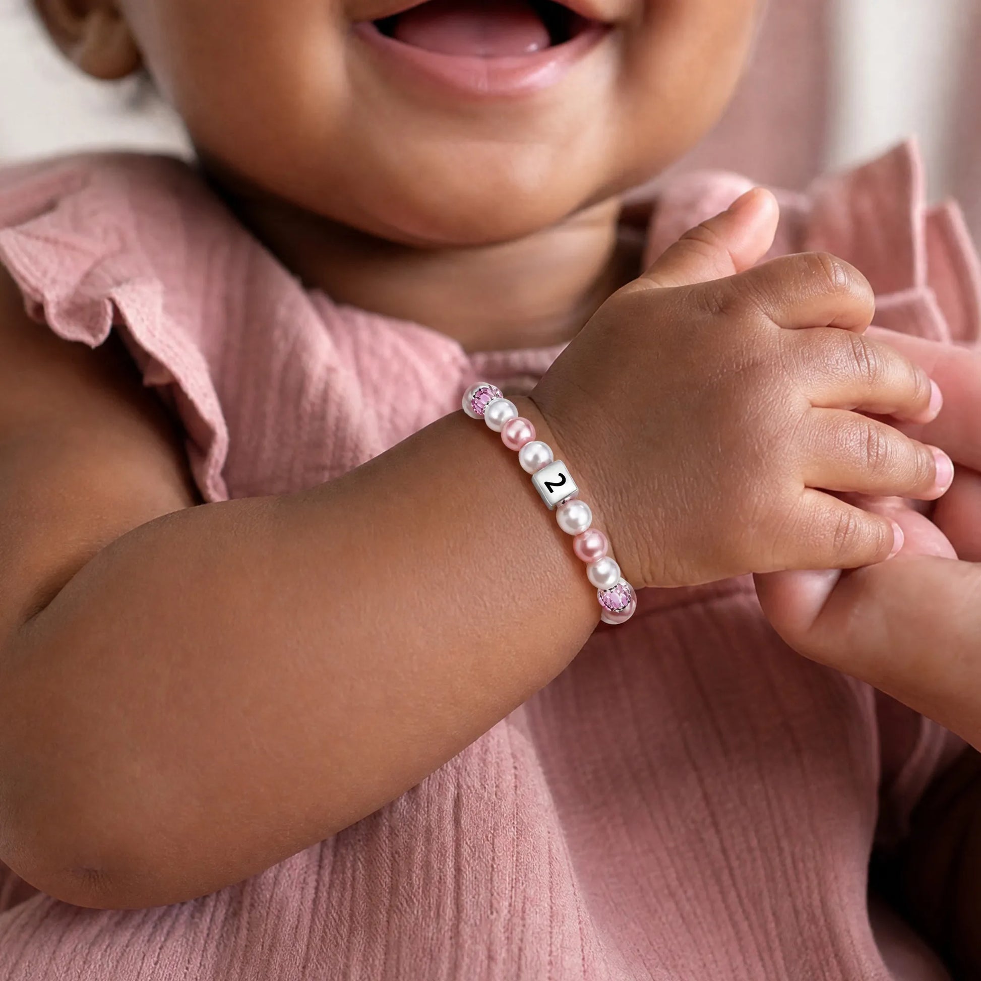 Little girl wearing pink pearl bracelet with number 2
