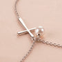 Close-up of silver cross necklace with pearl charm