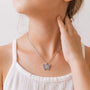 Small colorful butterfly pendant necklace on silver-tone chain, worn with white tank top