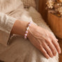 Pink ribbon cross beaded bracelet on a wrist with white and pink floral beads