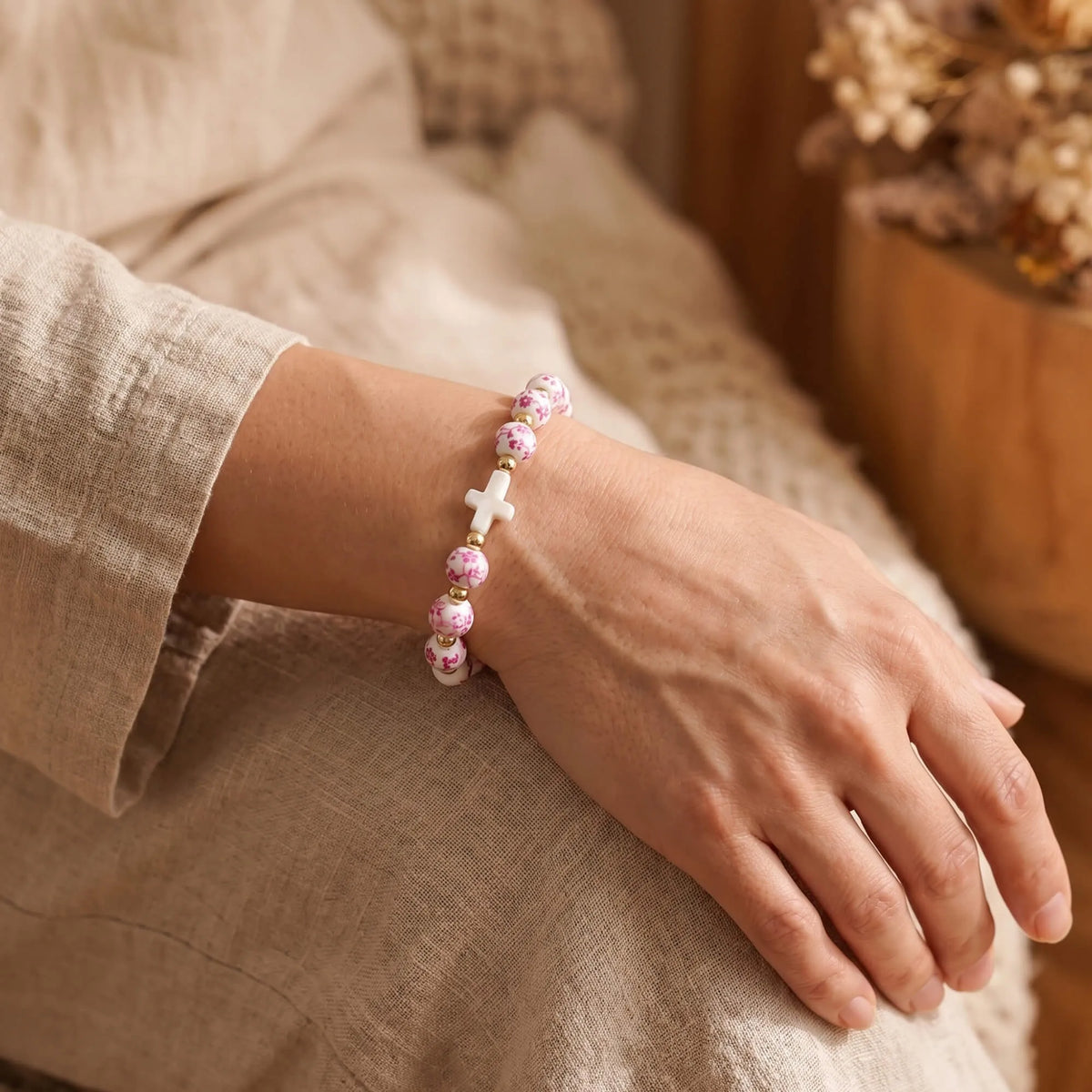 Pink ribbon cross beaded bracelet on a wrist with white and pink floral beads