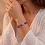 Amethyst bead bracelet with elephant charm on wrist, purple beads