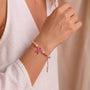 Pink beaded ribbon charm bracelet worn on wrist with brown cord ties