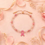 Pink beaded bracelet with gold beads and pink ribbon pendant on cord