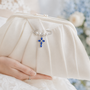 Something Blue Cross Pin attached to a white clutch bag
