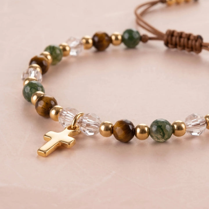Close-up of bracelet showing gold-tone cross charm and beads