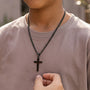Boy wearing black cross necklace outdoors