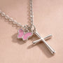 Close-up of silver cross necklace with pink butterfly charm