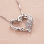 Close-up of silver heart necklace with angel wing and crystals
