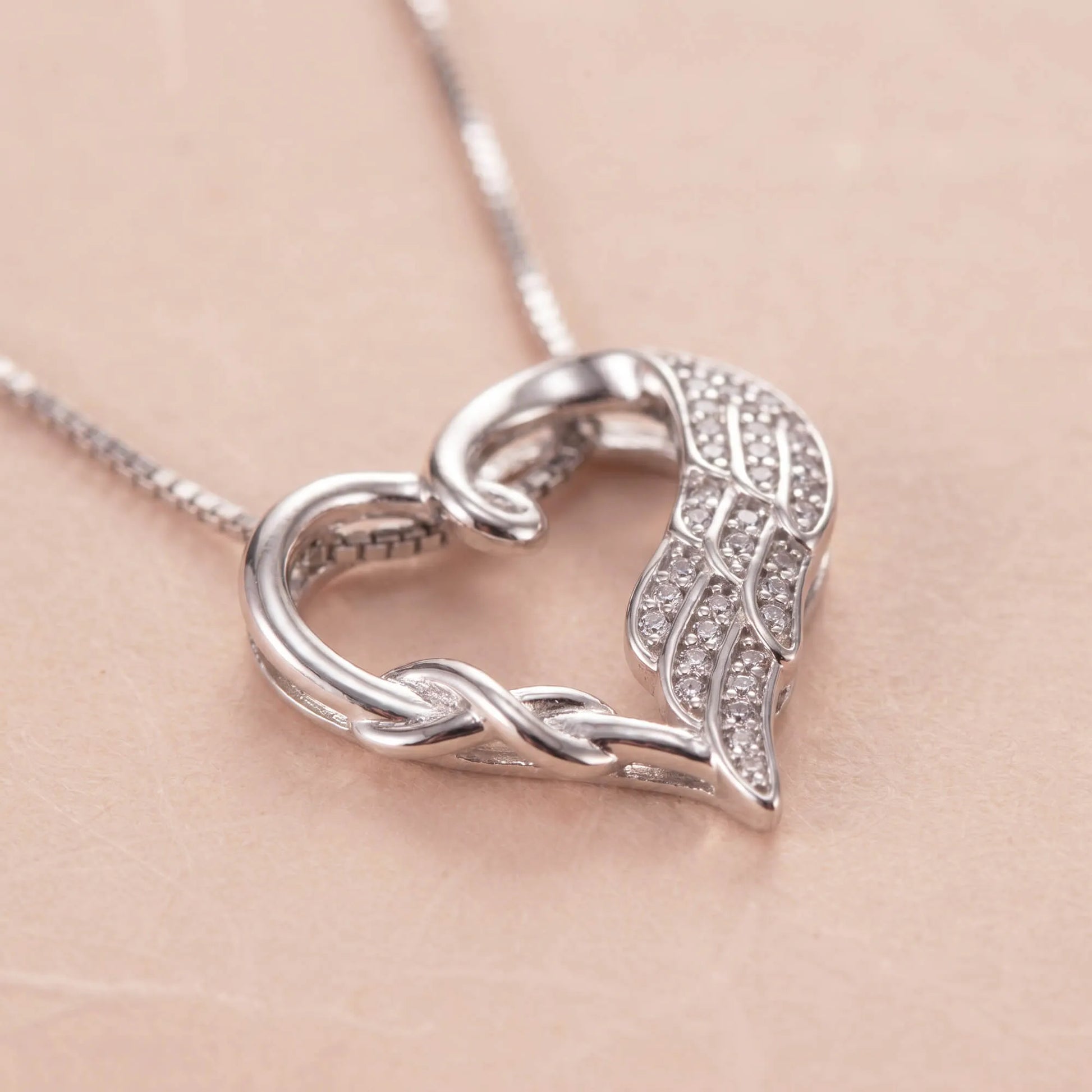 Close-up of silver heart necklace with angel wing and crystals