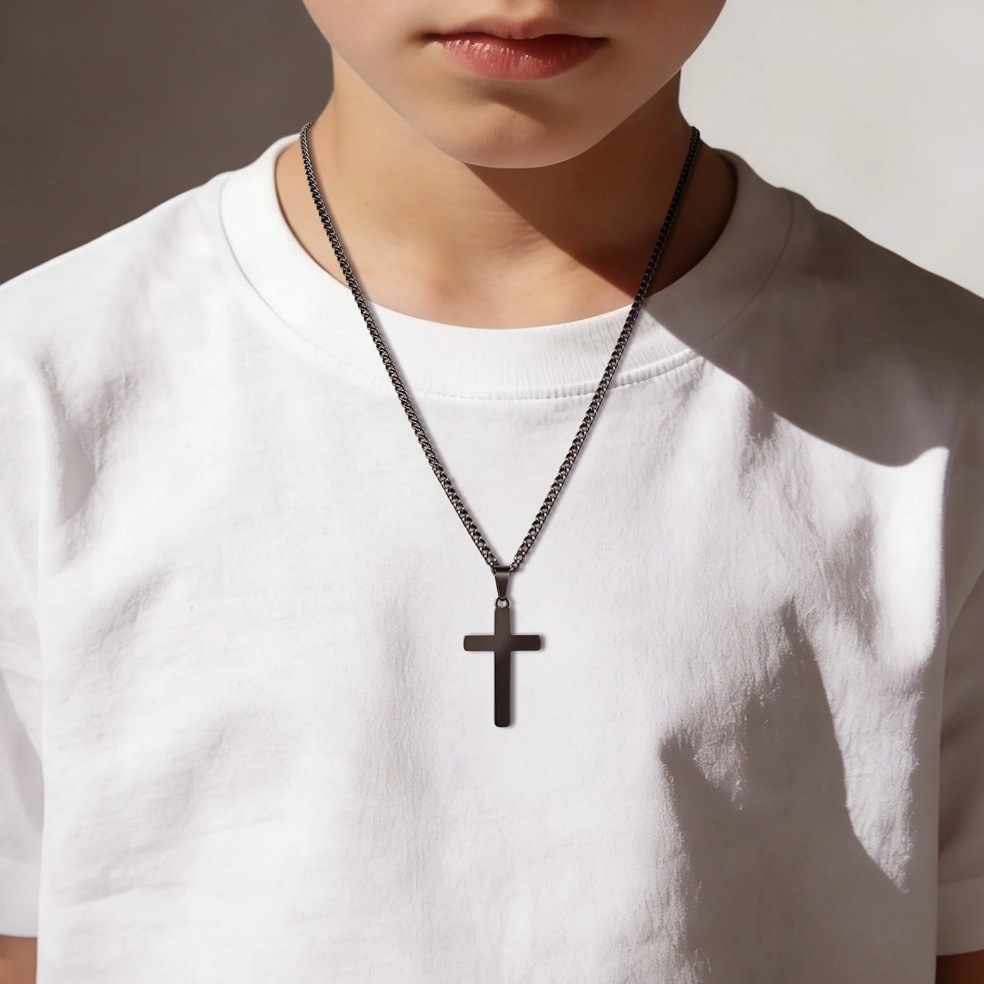 Boy wearing black cross necklace in profile