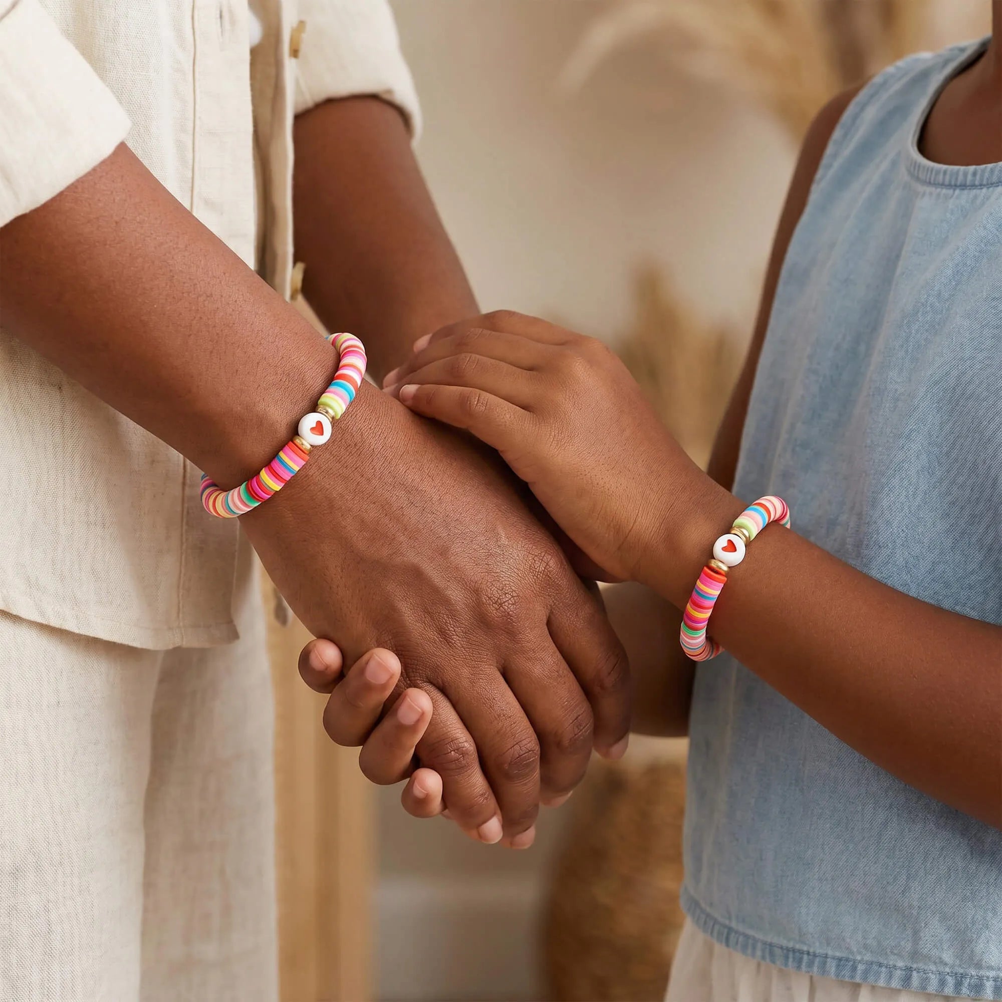 Two colorful bracelets held by mother and child