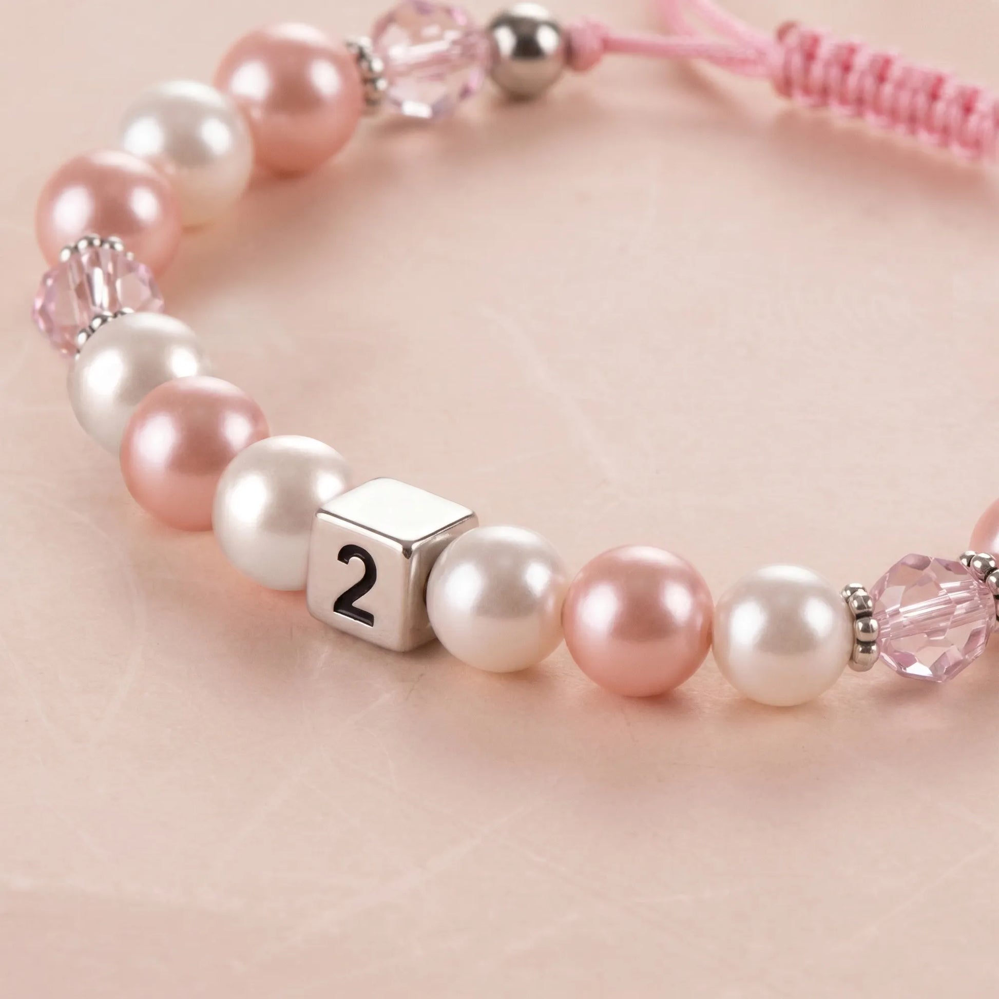Close-up of pink pearl bracelet with number 2