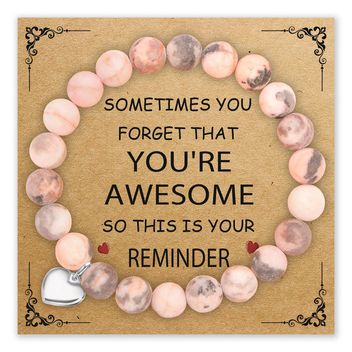 Bracelet with natural pink stones and silver-tone heart charm on a card