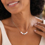 Woman wearing necklace with five crystal pearls and holding her neck