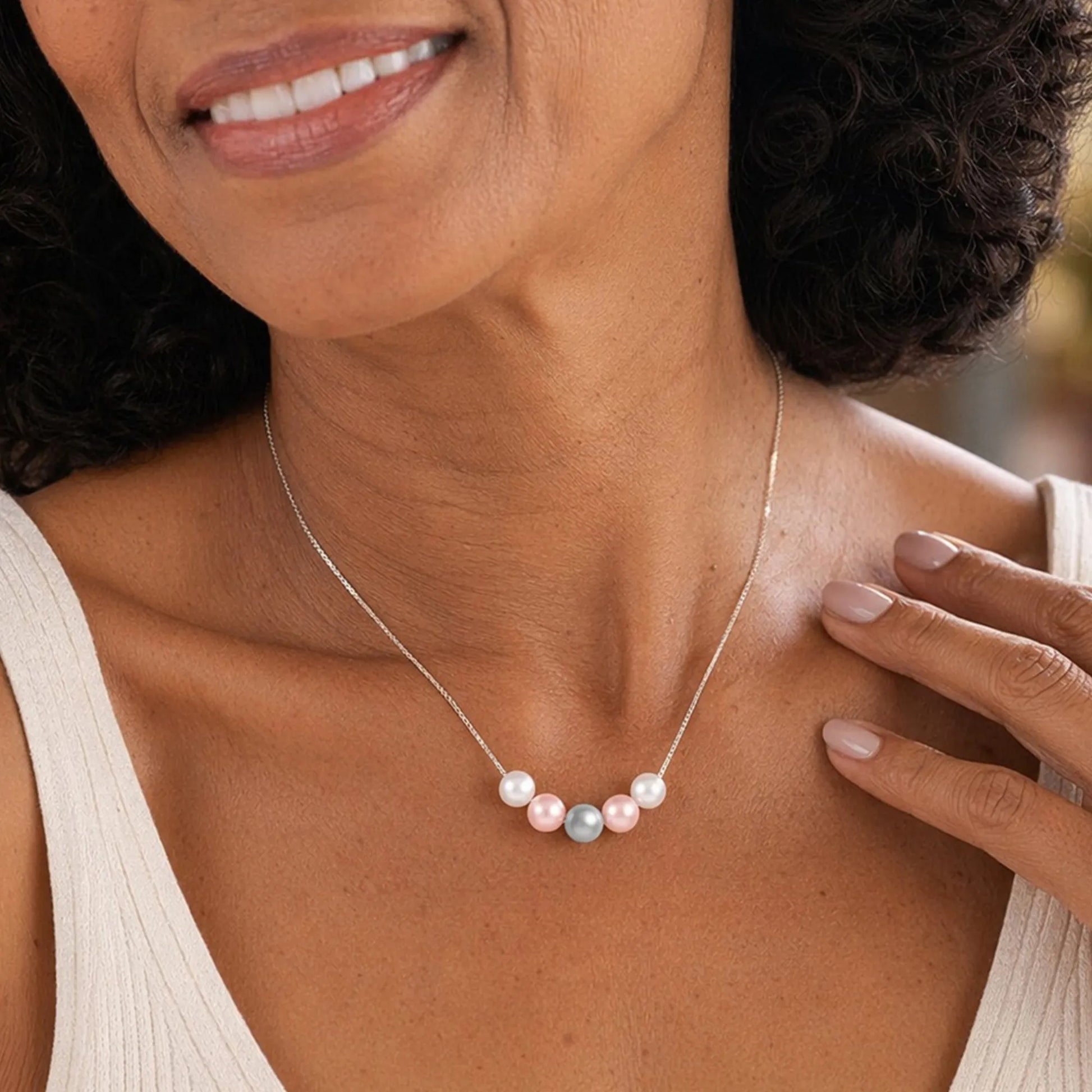 Woman wearing necklace with five crystal pearls and holding her neck