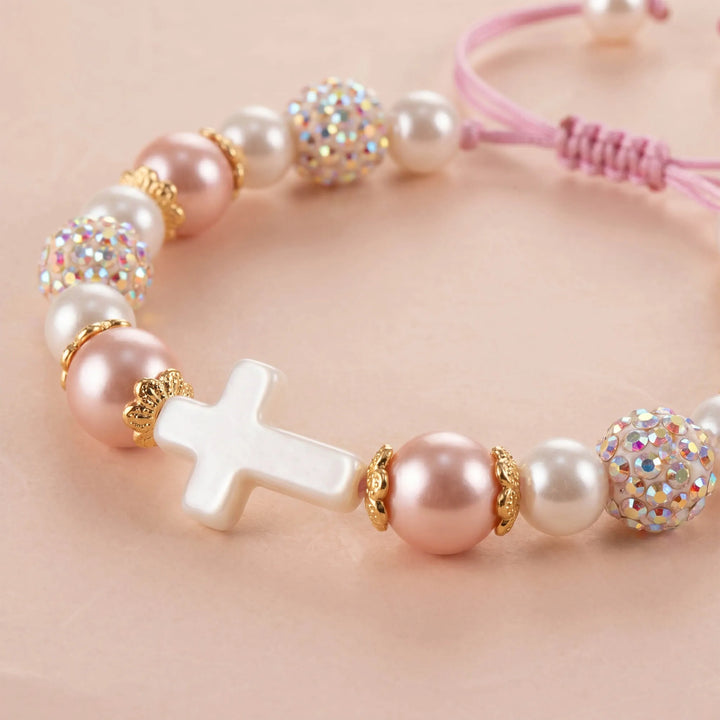 Close-up of bracelet featuring white cross and pink pearls