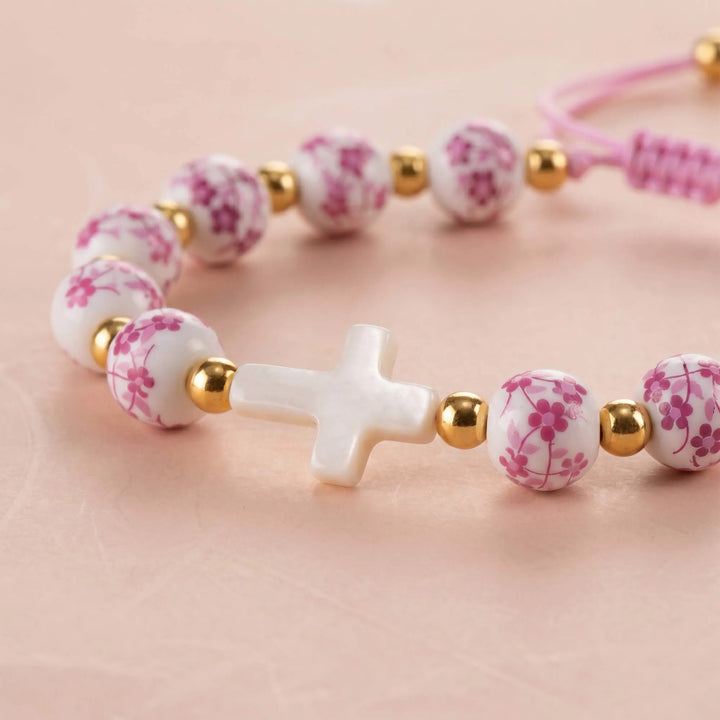 Close-up of bracelet showing pink floral beads and a white cross
