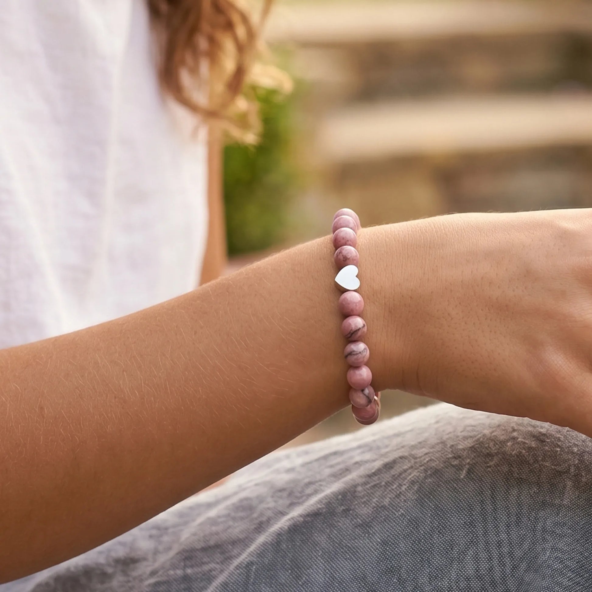 Model wearing pink zebra jasper bracelet with heart pendant