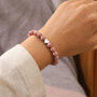 Close-up of pink zebra jasper bracelet with heart pendant on hand