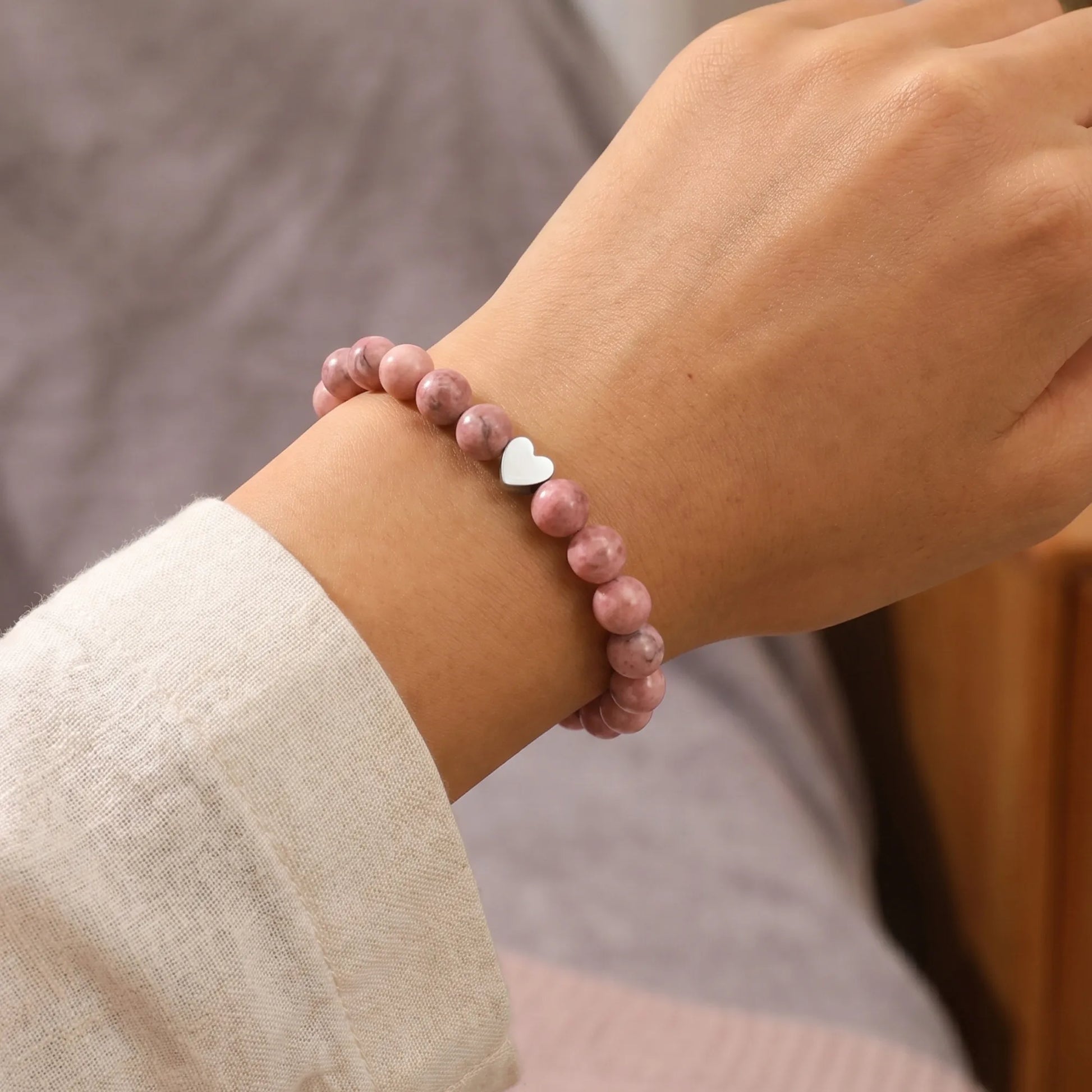 Close-up of pink zebra jasper bracelet with heart pendant on hand