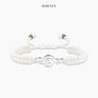 White bracelet with treble clef charm on a neutral background