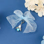 Angel charm with blue ribbon on blue background
