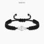 Black bracelet with treble clef charm on a neutral background