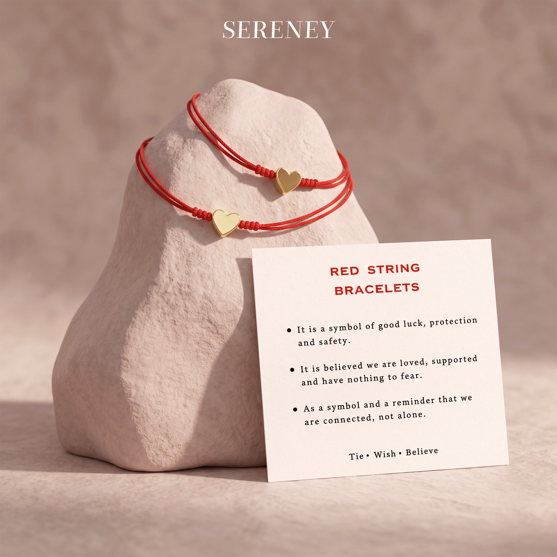 Red string bracelets with a card on a rock