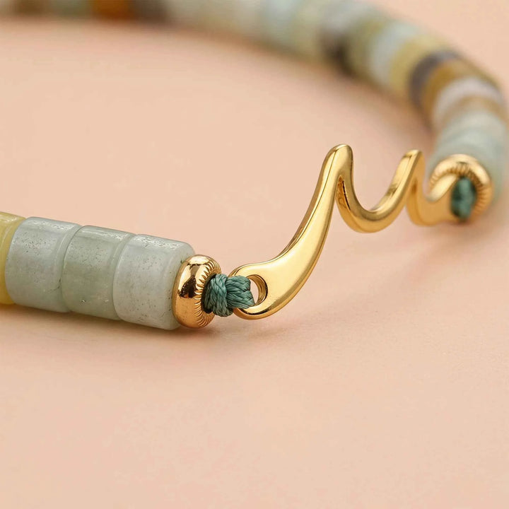 Gold ocean wave charm detail on bracelet with turquoise cord and pastel beads